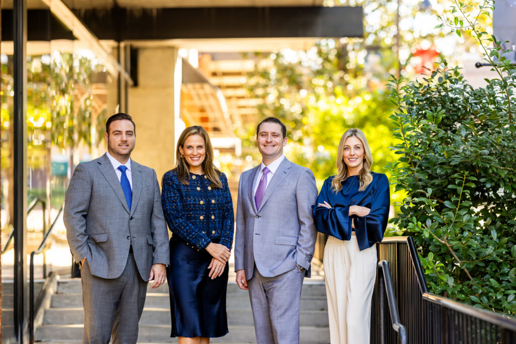 Four Capital City Consulting team members standing under an outdoor stairway